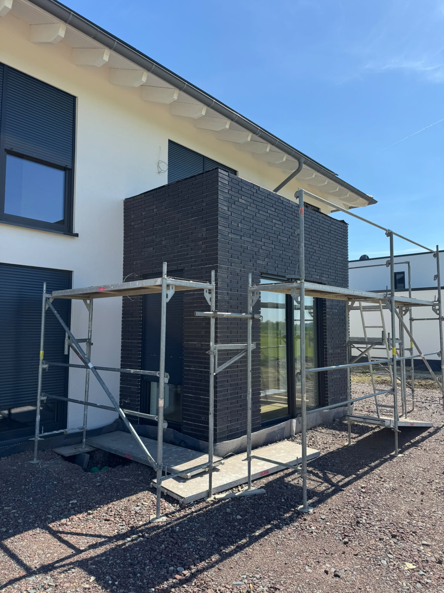 Moderner Anbau mit dunkler Klinkerfassade und Gerüst